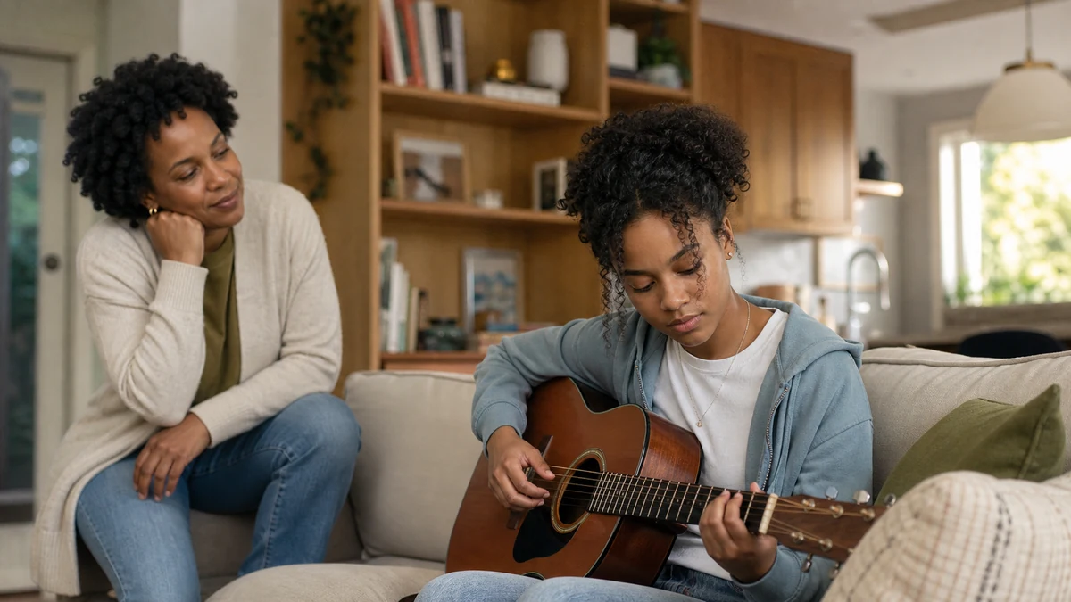 A mother watches warmly as her teenage daughter returns to practising guitar